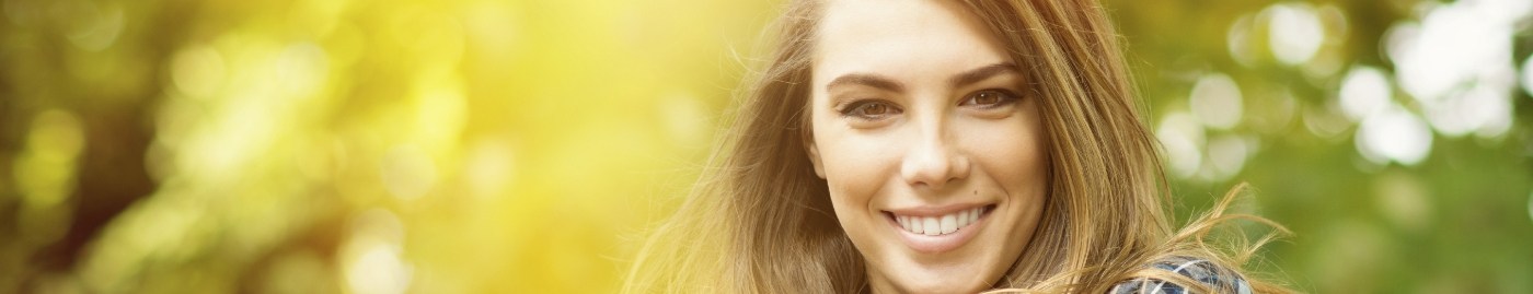 Brunette woman smiling outdoors after cosmetic dentistry in Albuquerque