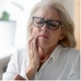 Woman wincing and holding her cheek in pain