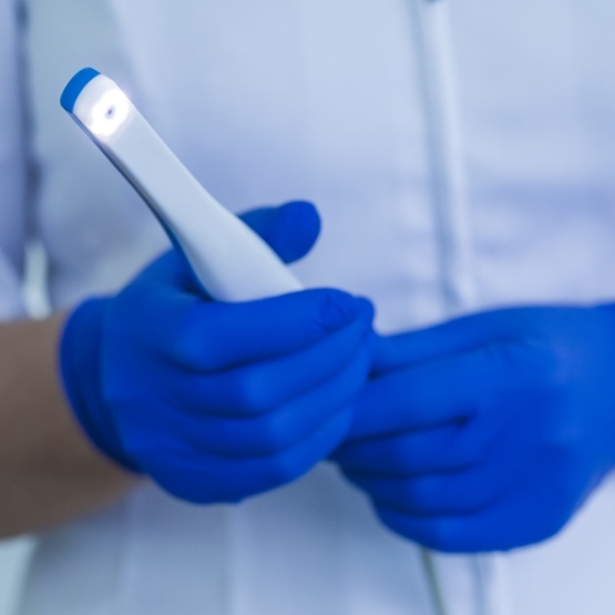 Dental team member holding a white pen like intraoral camera