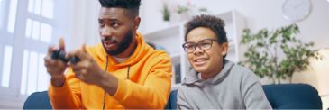 Father and son sitting on couch playing video games