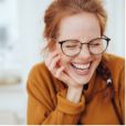 Smiling woman with glasses resting her chin in her hand