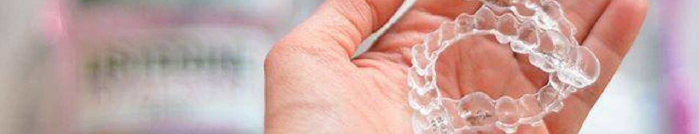 Hand holding two Invisalign clear aligners in Albuquerque