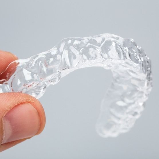 Hand holding an Invisalign clear aligner