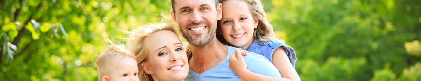 Family of four smiling outdoors on sunny day