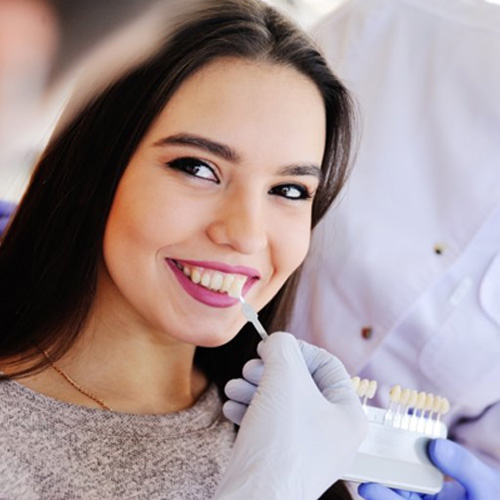 Dentist using shade guide on female patient
