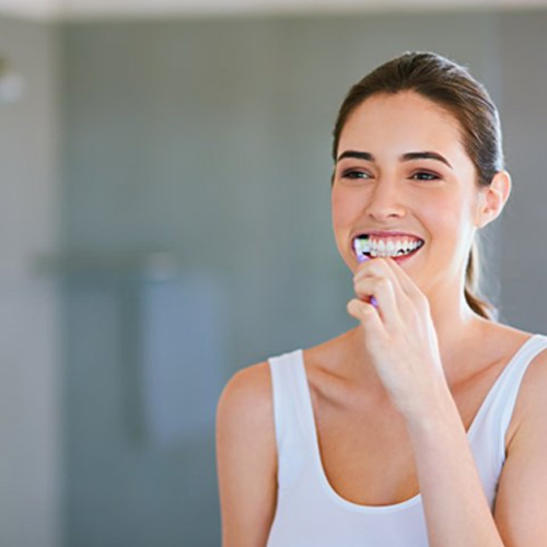 Woman brushing her teeth at home