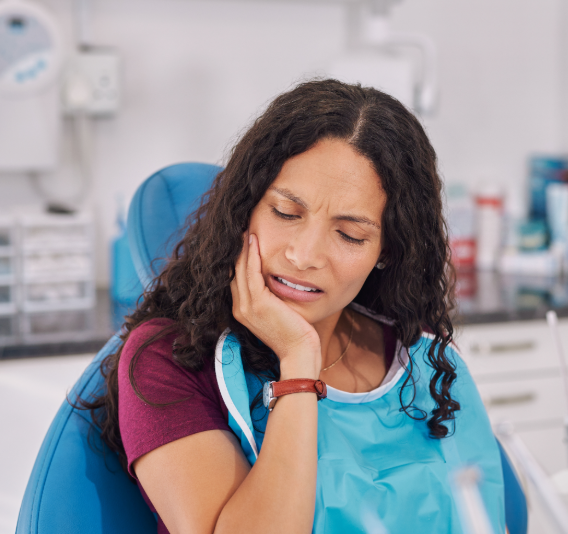Patient in dental chair hodling jaw in pain