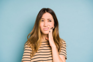 Woman rubbing her jaw and looking uncertain
